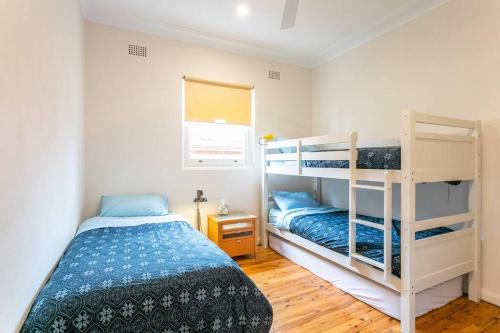 a bedroom with two bunk beds and a window at Beach House Close to Manly in Sydney