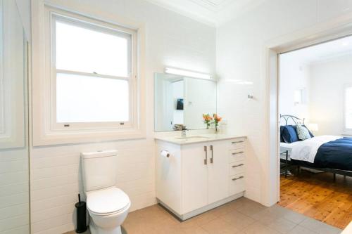 a white bathroom with a toilet and a bed at Beach House Close to Manly in Sydney