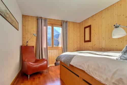 1 dormitorio con 1 cama, 1 silla y 1 ventana en Cable Car 2 Min Walk High End Apartment Sauna, en Champéry