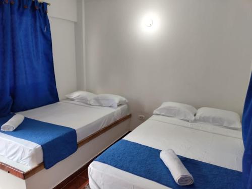 2 camas en una habitación pequeña con cortinas azules en Hotel la Isabela By Marbar, en Villeta