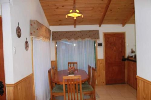 Cabaña Emilia في سانتياغو: غرفة طعام مع طاولة وكراسي وسقف