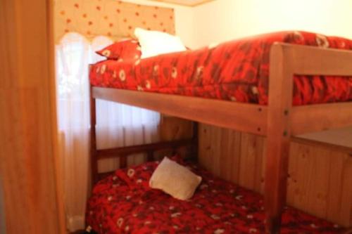 1 dormitorio con 2 literas y manta roja en Cabaña Emilia en Santiago