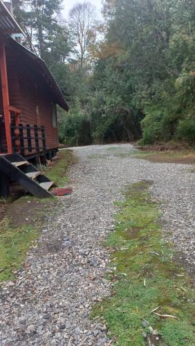 a gravel road next to a house and a building at Agradable Cabaña inserta en bosque nativo in Pucón
