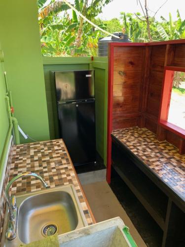 a kitchen with a sink and a black refrigerator at Green Queendom Farm and Lodging in Oracabessa
