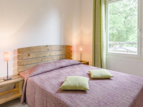 um quarto com uma cama com duas almofadas em Nice apartment with a dishwasher near a recreational lake em Aureilhan