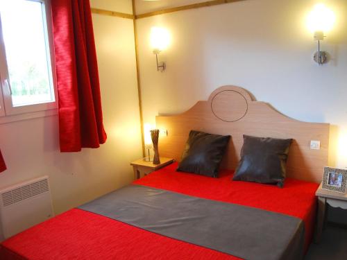 une chambre avec un lit rouge avec deux oreillers dans l'établissement Chalet in France with Garden Terrace, à Castelmoron-sur-Lot