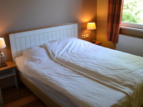 a bed in a bedroom with two lamps and a window at Bungalow in Netherlands with Ship-Like Design in 's-Gravenzande