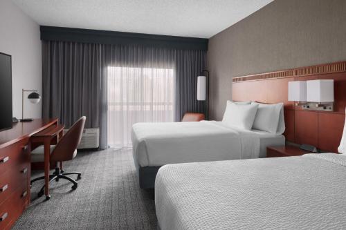a hotel room with two beds and a desk at Courtyard by Marriott New Haven Wallingford in Wallingford