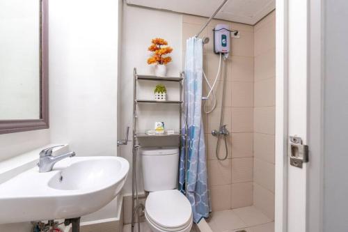 a bathroom with a toilet and a sink and a shower at PineSuites Relaxing 2-bedroom condo with pool and garden view in Tagaytay