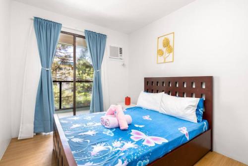 a bedroom with a bed with a stuffed animal on it at PineSuites Relaxing 2-bedroom condo with pool and garden view in Tagaytay
