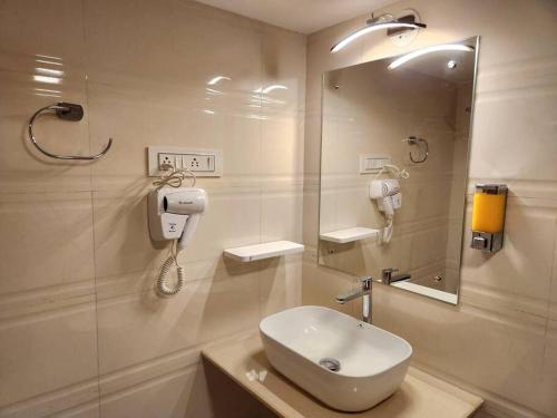 a white bathroom with a sink and a mirror at BeachWalk Tulip Apartments Vagator in Vagator