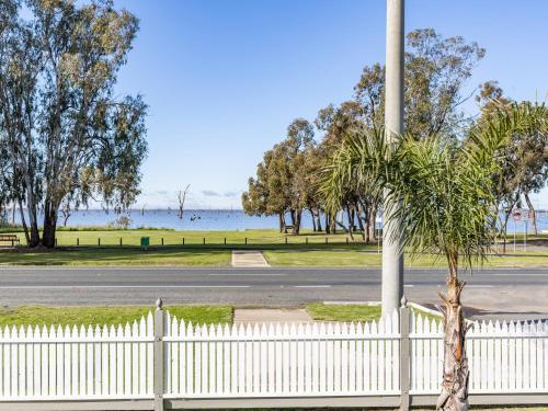 a white fence with a palm tree next to a road at NRMA Yarrawonga Mulwala Holiday Park in Mulwala