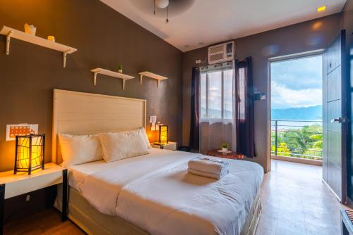 een slaapkamer met een groot bed en een groot raam bij The Ridge Coron in Coron