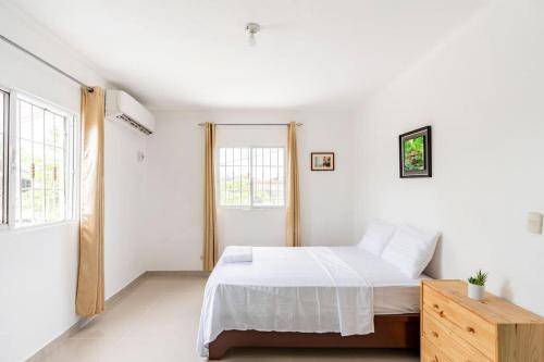 a white bedroom with a bed and two windows at SDQ airport & Samana bus near Bamboo in Santo Domingo