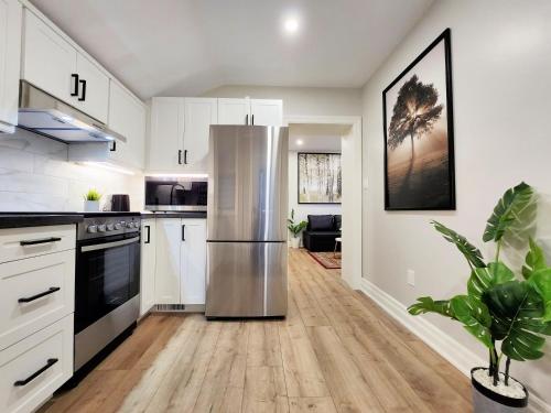a kitchen with white cabinets and a stainless steel refrigerator at The Cozy Cove Modern King-Bedroom Full Apartment in St. Catharines