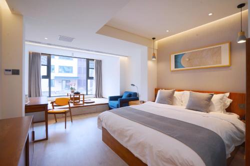 een slaapkamer met een bed, een bureau en een stoel bij Jiushui Heyuan Art Design Hotel in Qingdao