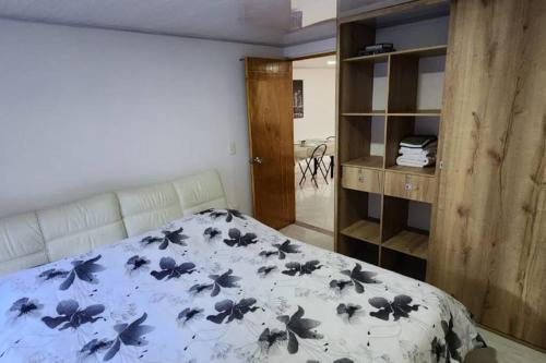 een slaapkamer met een bed met een blauwe en witte deken bij Terranova, apto en el Salvador in Medellín