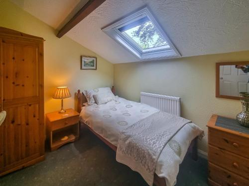 a bedroom with a large bed with a skylight at Harwood Dale Cottage in Kendal