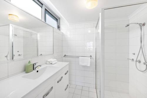 a white bathroom with a shower and a sink at Amazing beach view and perfect location Kirra in Gold Coast