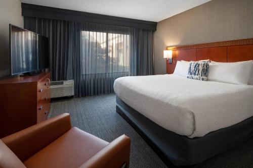 a hotel room with a large bed and a couch at Courtyard by Marriott Bakersfield in Bakersfield