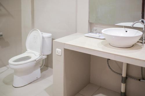 a white bathroom with a sink and a toilet at WISMA KUSUMA HOTEL in Kedungdowo