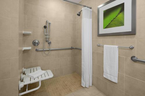 a bathroom with a shower with a television on the wall at Courtyard By Marriott Houston Kingwood in Kingwood