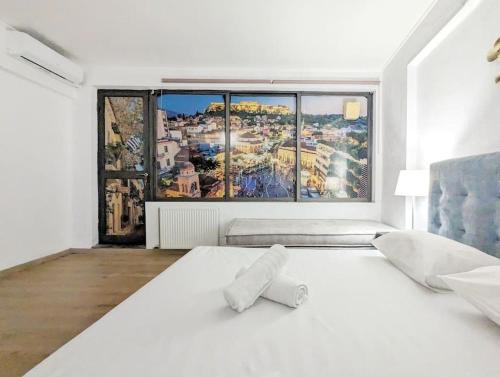 una camera da letto con un grande letto bianco con una grande finestra di Athens Divas King Suite ad Atene