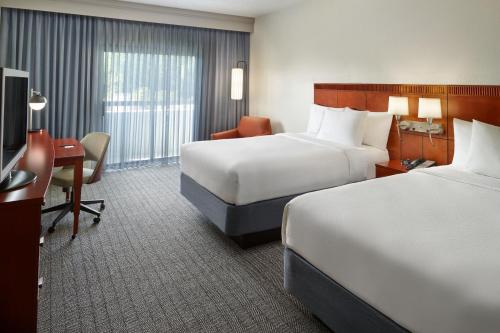 a hotel room with two beds and a television at Courtyard by Marriott Atlanta Executive Park/Emory in Atlanta