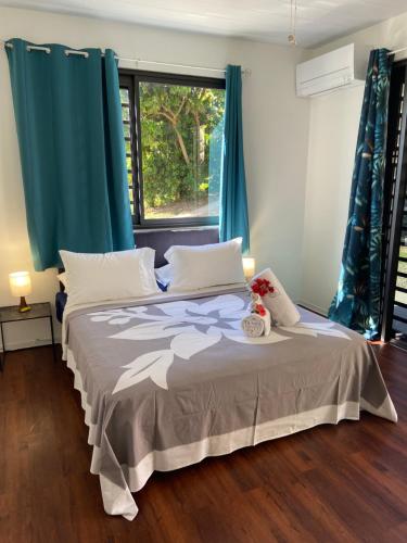 sypialnia z łóżkiem z niebieskimi zasłonami i oknem w obiekcie Manaeva L6 w mieście Faaa