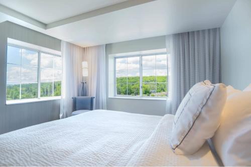 a bedroom with a bed and two windows at Courtyard by Marriott Lenox Berkshires in Lenox
