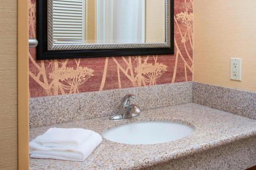 a bathroom sink with a towel and a mirror at Courtyard by Marriott Peoria in Peoria