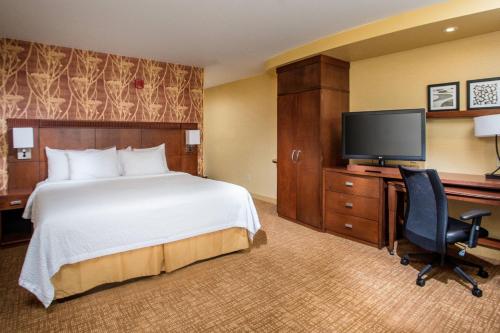 a hotel room with a bed and a flat screen tv at Courtyard by Marriott Peoria in Peoria