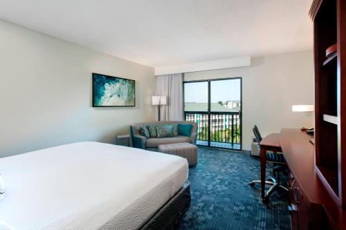 a hotel room with a bed and a desk and a chair at Courtyard by Marriott Myrtle Beach Barefoot Landing in Myrtle Beach
