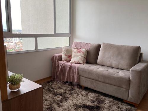 a living room with a couch and a window at Melhor Ap Poços de Caldas in Poços de Caldas