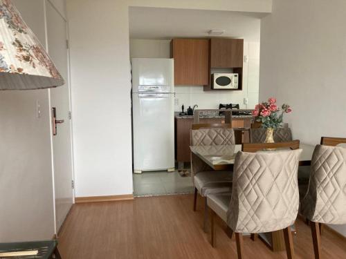 a kitchen with a table and a white refrigerator at Melhor Ap Poços de Caldas in Poços de Caldas