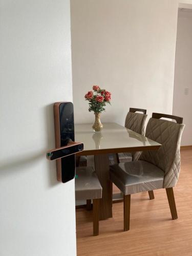 a table and chairs with a vase of flowers on it at Melhor Ap Poços de Caldas in Poços de Caldas
