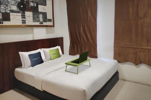 - une chambre avec un lit doté d'un ordinateur portable vert dans l'établissement Urbanview Os Residence Medan by RedDoorz, à Medan