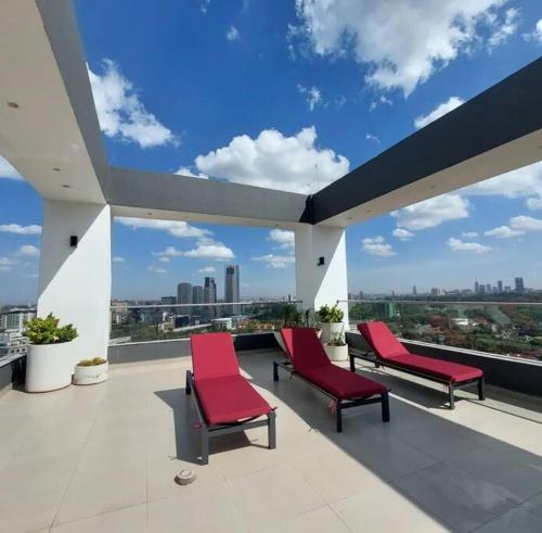 a balcony with red chairs and a view of a city at Modern home in Nairobi Escada in Nairobi