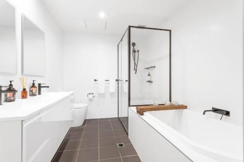 Un baño blanco con bañera y inodoro. en Le Maison at the Beach, en Huskisson