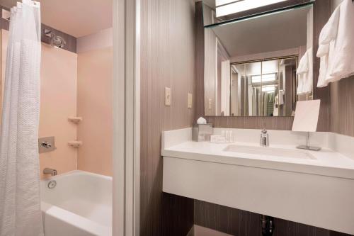 a bathroom with a sink and a tub and a mirror at Courtyard by Marriott Scottsdale Old Town in Scottsdale