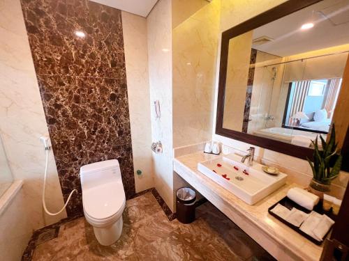 a bathroom with a toilet and a sink and a mirror at Muong Thanh Luxury Nhat Le Hotel in Dong Hoi