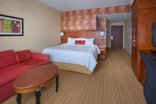 um quarto de hotel com uma cama e um sofá vermelho em Courtyard Boston-South Boston em Boston