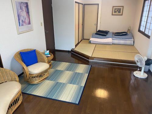 a room with two beds and a chair and a table at ゲストハウス宮崎 guesthouse miyazaki バックパッカー向け個室旅人宿 P有 in Miyazaki