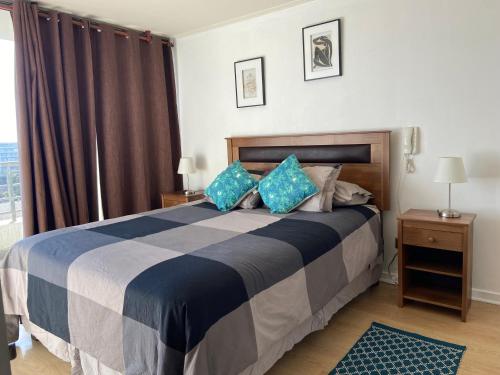 - une chambre avec un grand lit et des oreillers bleus dans l'établissement Agradable departamento, frente a la Quinta Vergara, à Viña del Mar