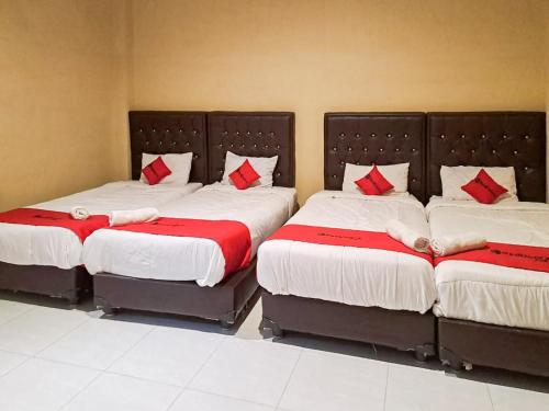 two beds with red pillows in a room at RedDoorz Syariah At Harley Hotel Sabang in Sabong