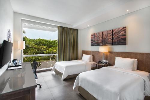 a hotel room with two beds and a window at Hilton Garden Inn Bali Ngurah Rai Airport in Kuta