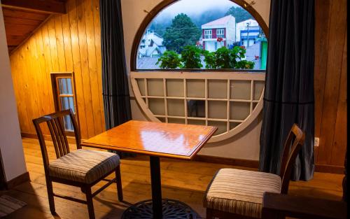 a table and two chairs in front of a window at The Golf Green City Bungalow in Nuwara Eliya