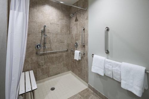a bathroom with a shower with white towels at Courtyard by Marriott Dallas Plano/Richardson in Plano