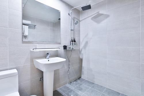 a white bathroom with a sink and a shower at The First Hotel in Changwon
