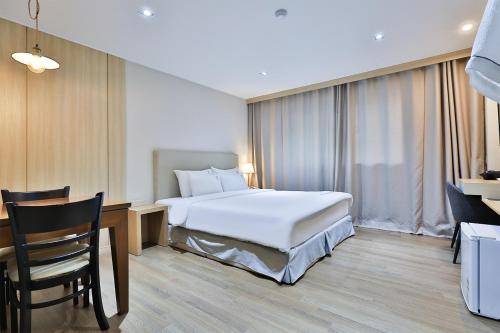 a hotel room with a bed and a desk and a chair at The First Hotel in Changwon
